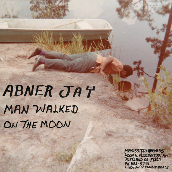 Man Walked on the Moon by Abner Jay on Mississippi Records (the album artwork is a colour photograph of the artist lying on a bank of a lake, looking into the water; the artist name and album title are handwritten in black uppercase text over the photograph)