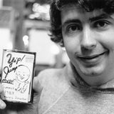 Black and white photograph of Daniel Johnston holding a cassette copy of Yip/Jump Music