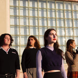 Colour band photograph of The Ophelias stood outside a large window looking in different directions