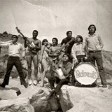 Black and white band photograph of Los Sideral's stood together on rocks with their instruments