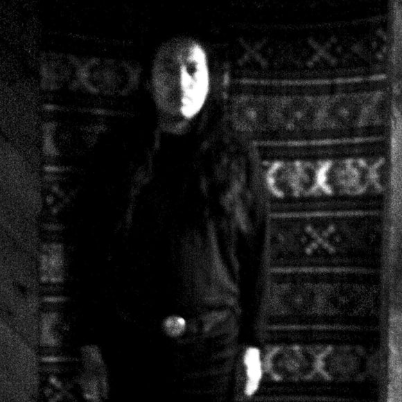 Stateless by Tashi Dorji on Drag City Records (the album cover depicts an grainy, dark, and out-of-focus black and white photograph of Tashi Dorji standing in front of a patterned wall hanging. There is no text on the front of the album sleeve)